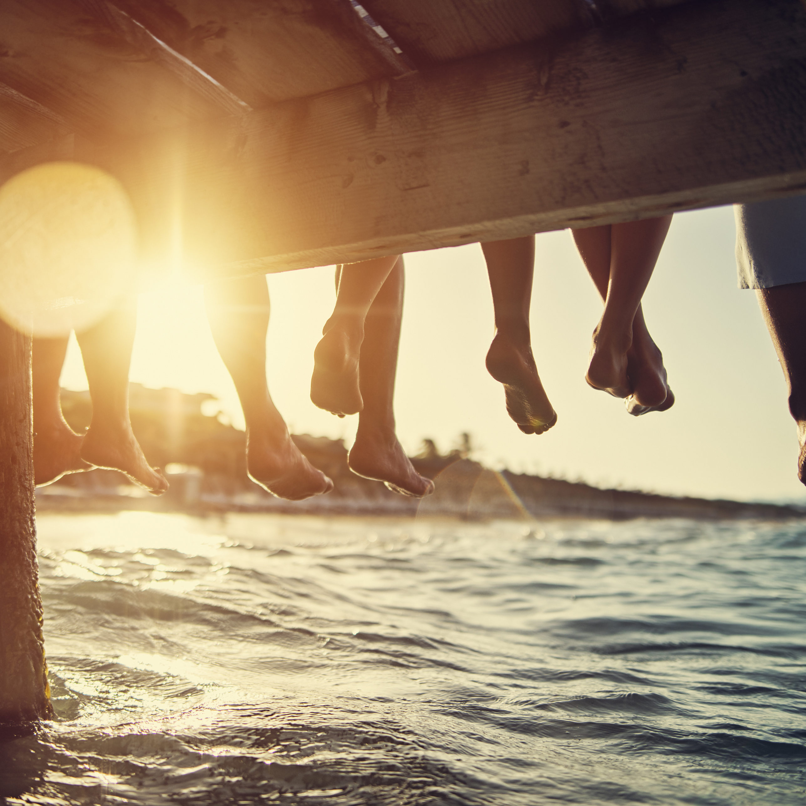 Five people having fun sitting on pier. Feet shot from below the pier. Sunny summer day evening.
Nikon D850